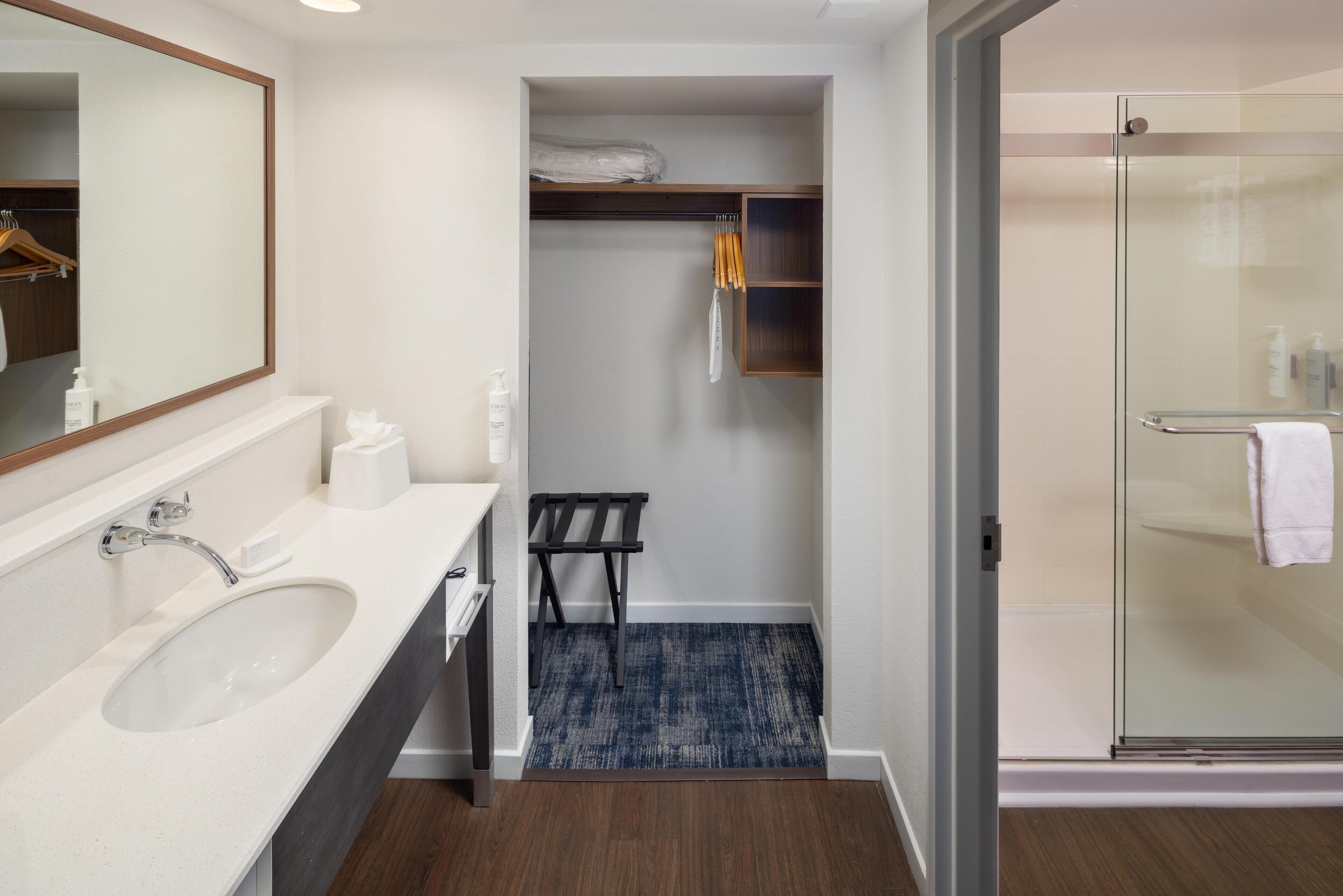 A modern bathroom with a sink, mirror, and shower.