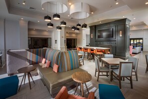 A modern hotel lobby with a seating area, a bar, and a television mounted on the wall. - Hampton Inn & Suites Asheville Airport (Fletcher)
