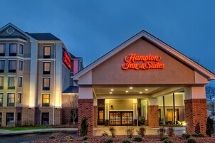 Un hotel con un llamativo letrero de neón, fachada de ladrillo y una entrada bien iluminada.