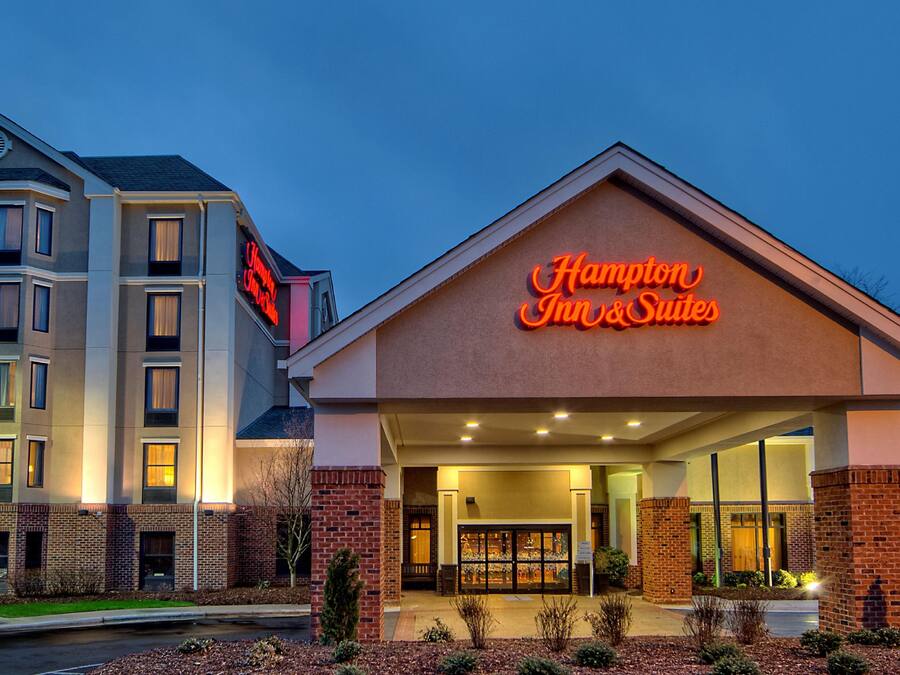 A hotel with a prominent neon sign, a brick facade, and a well-lit entrance.