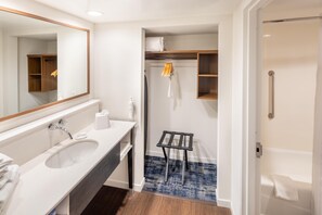 A bathroom with a sink, mirror, towel rack, and a shower area.