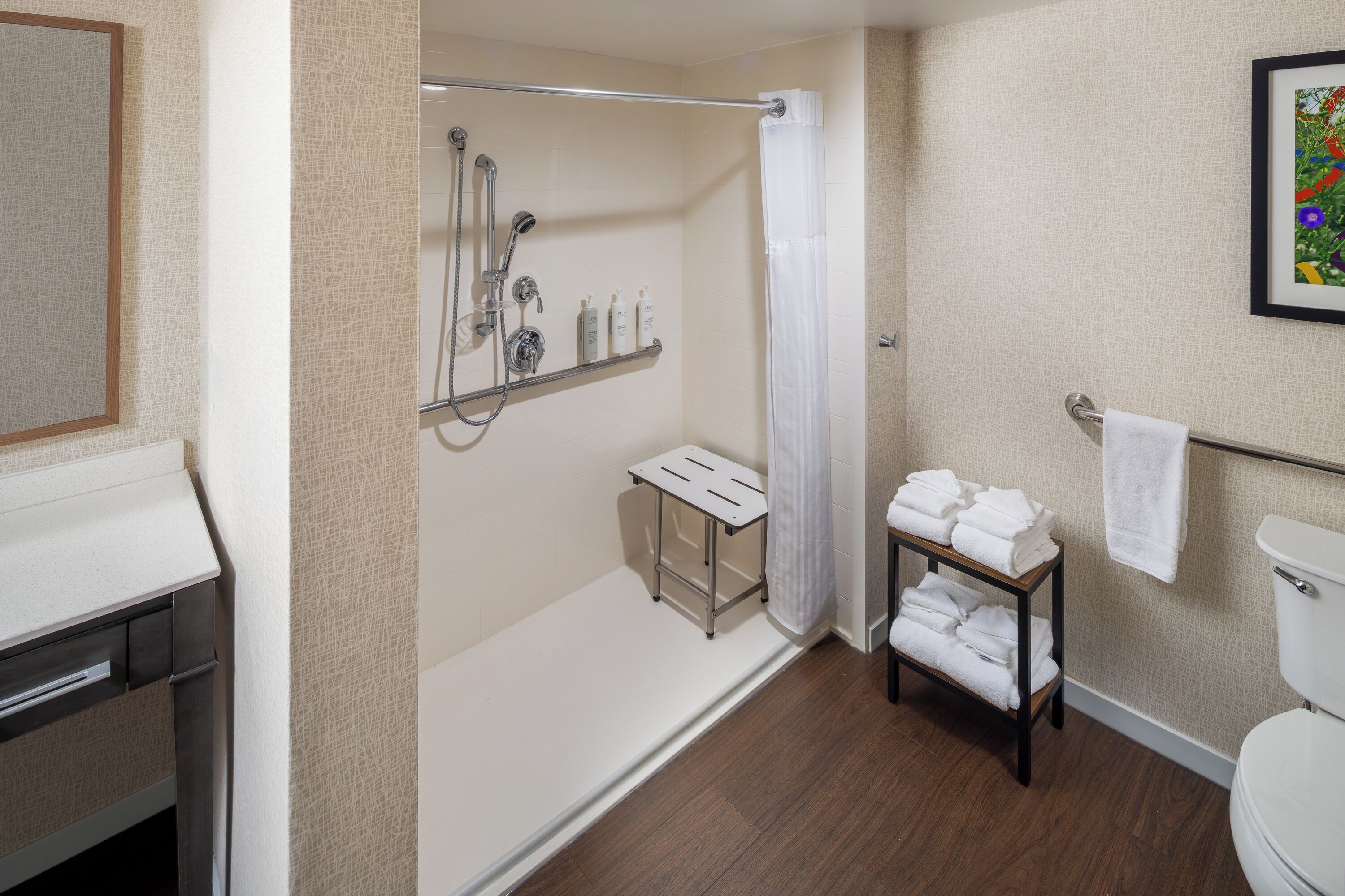 A bathroom with a shower, toilet, and a shelf with towels.
