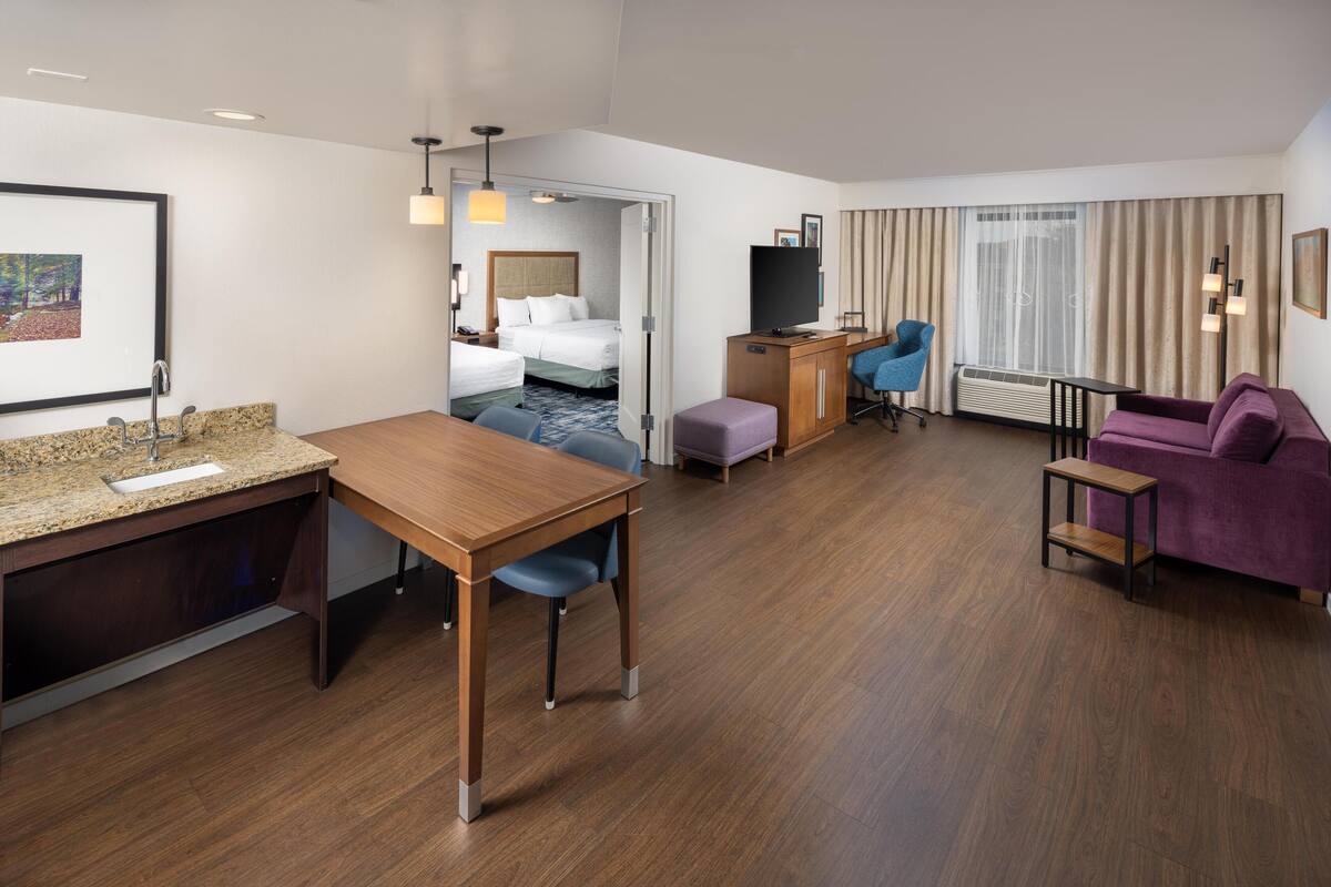 Una habitación de hotel con escritorio de madera, televisor, sofá y cama.