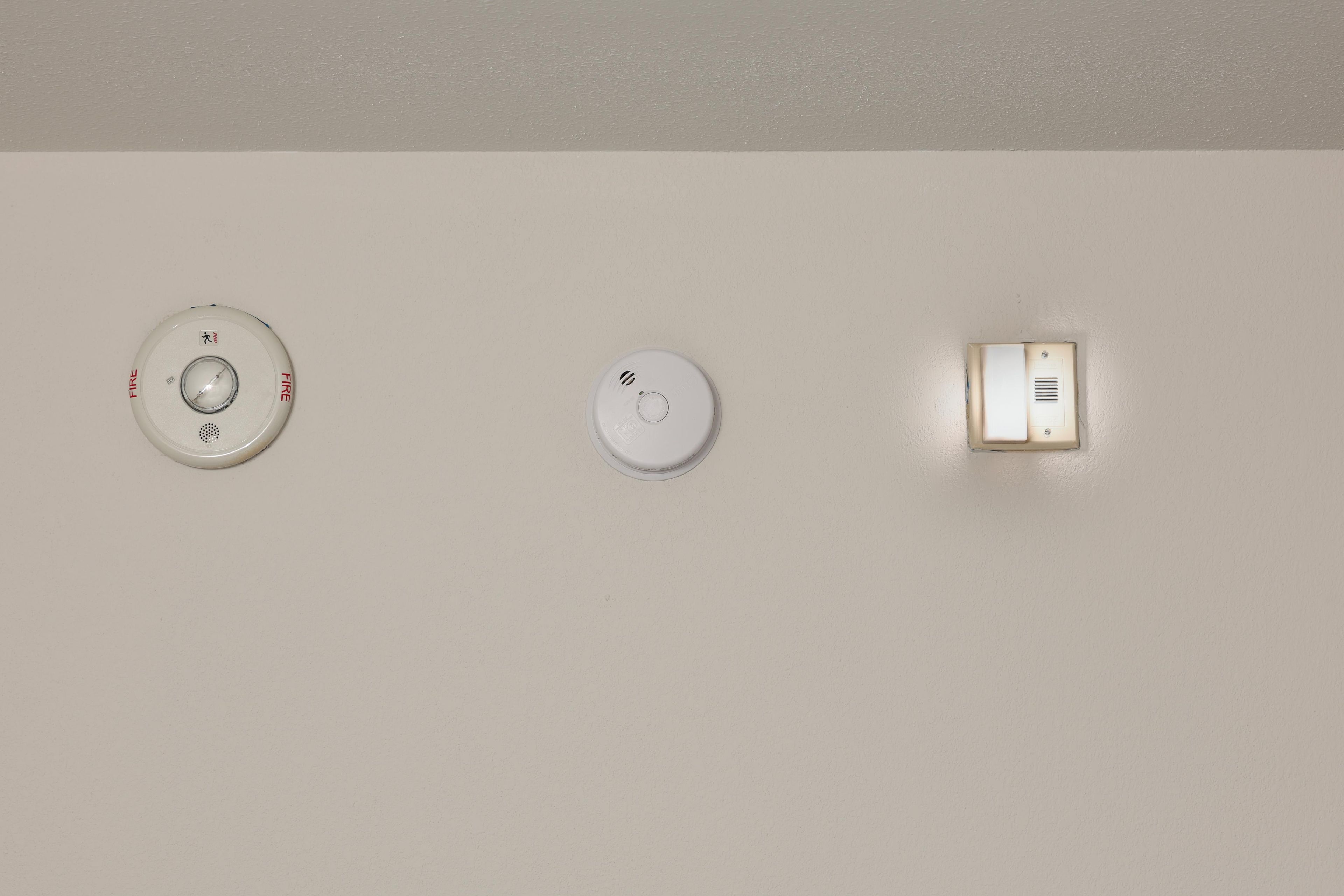 Three wall-mounted smoke detectors on a plain wall.