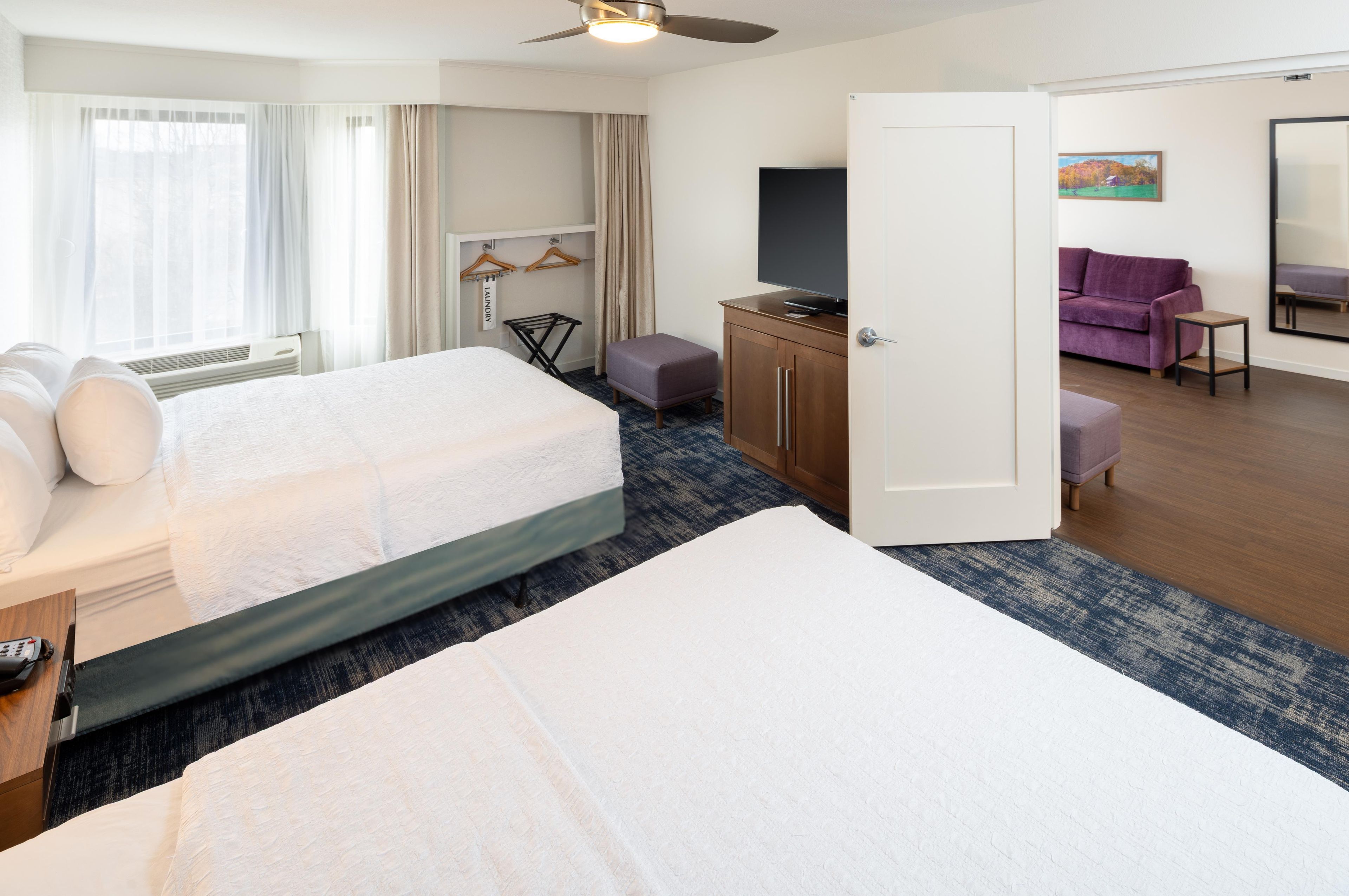 A hotel room with a bed, a desk, a wardrobe, a television, and a bathroom.