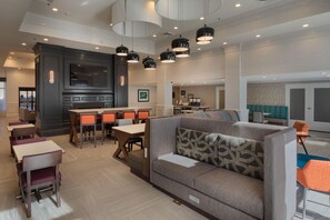 A modern hotel lobby with a seating area, a kitchen, and a television. - Hampton Inn & Suites Asheville Airport (Fletcher)