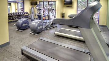 A gym with treadmills, elliptical machines, and a wall-mounted TV.