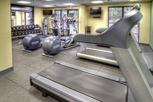 A gym with treadmills, elliptical machines, and a wall-mounted TV.