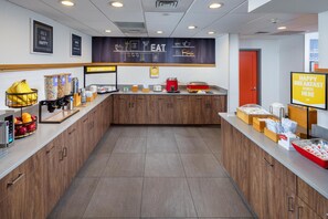 A modern breakfast area with a counter, kitchen appliances, and a sign indicating breakfast services.