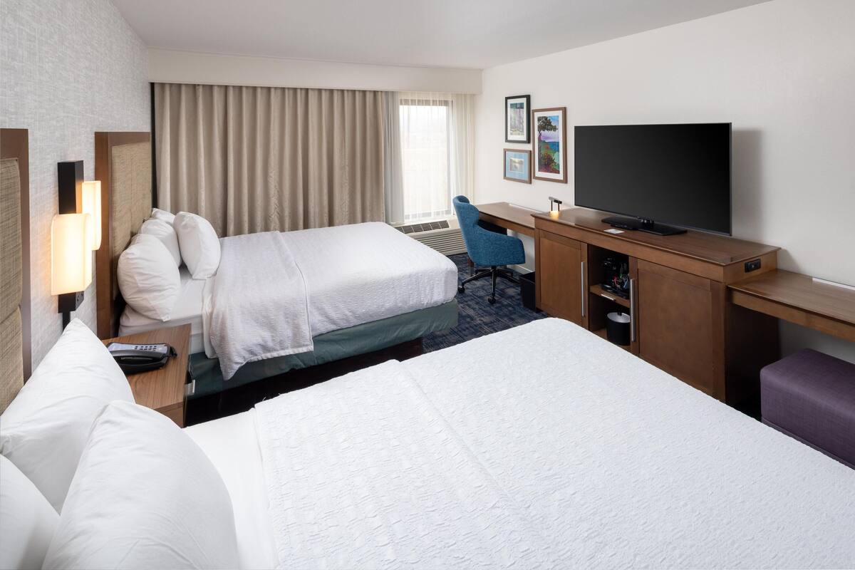 Una habitación de hotel con dos camas, un escritorio, un televisor y una silla.