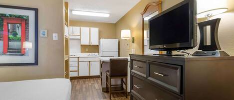 Une chambre d’hôtel comprenant un lit, un bureau avec une chaise, une télévision et un minibar.
