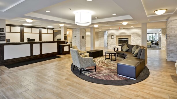 A modern lobby with a reception desk, seating area, and a fireplace. - Homewood Suites by Hilton Dulles Int'l Airport (Herndon)