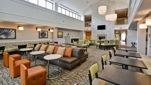 A spacious lobby with high ceilings, multiple seating areas, and a central fireplace. - Homewood Suites by Hilton Dulles Int'l Airport (Herndon)