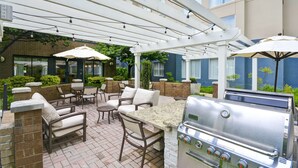 An outdoor patio with a grill, seating, and umbrellas. - Homewood Suites by Hilton Dulles Int'l Airport (Herndon)