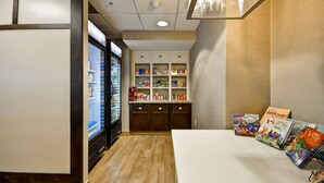A kitchen area with a refrigerator, a pantry with various food items, and a table with children's books. - Homewood Suites by Hilton Dulles Int'l Airport (Herndon)