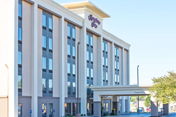 A modern hotel with a 'Welcome' sign and a 'Clearance 12'6' sign.
