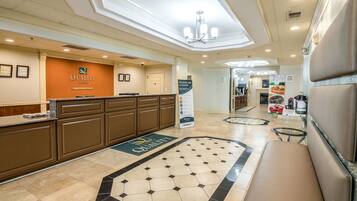A hotel reception area with a reception desk, a bench, and a sign for Quality Inn by Choice Hotels.