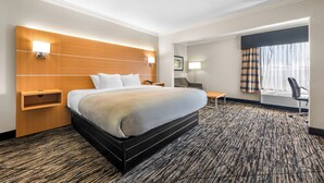 Ein Hotelzimmer mit einem großen Bett, Nachttischen, einem Schreibtisch und einem Sessel.