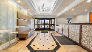 Eine Hotelhalle mit einer Rezeption, einer Sitzecke und Blick durch Glastüren.
