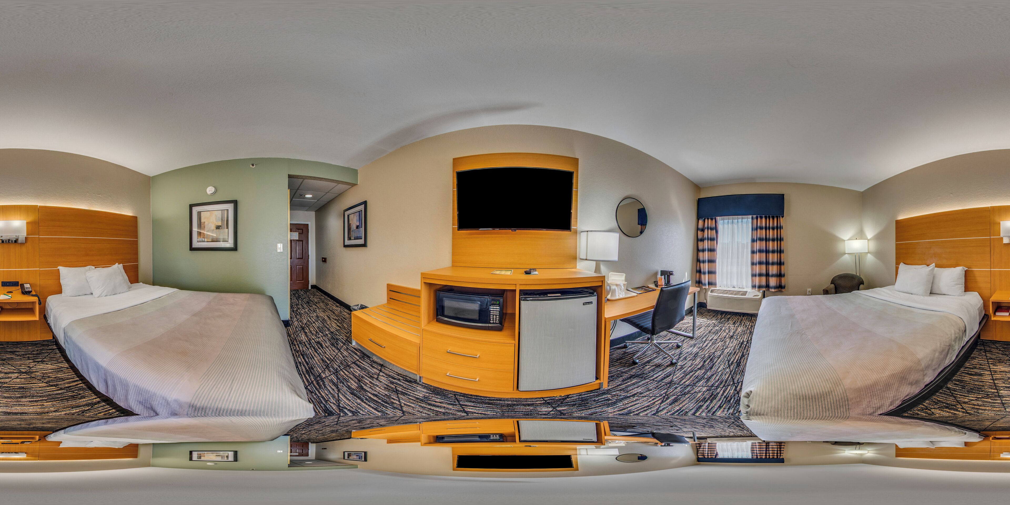 A hotel room with two beds, a desk, a television, and a microwave.