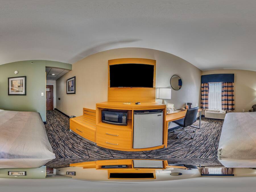 A hotel room with two beds, a desk, a television, and a microwave.