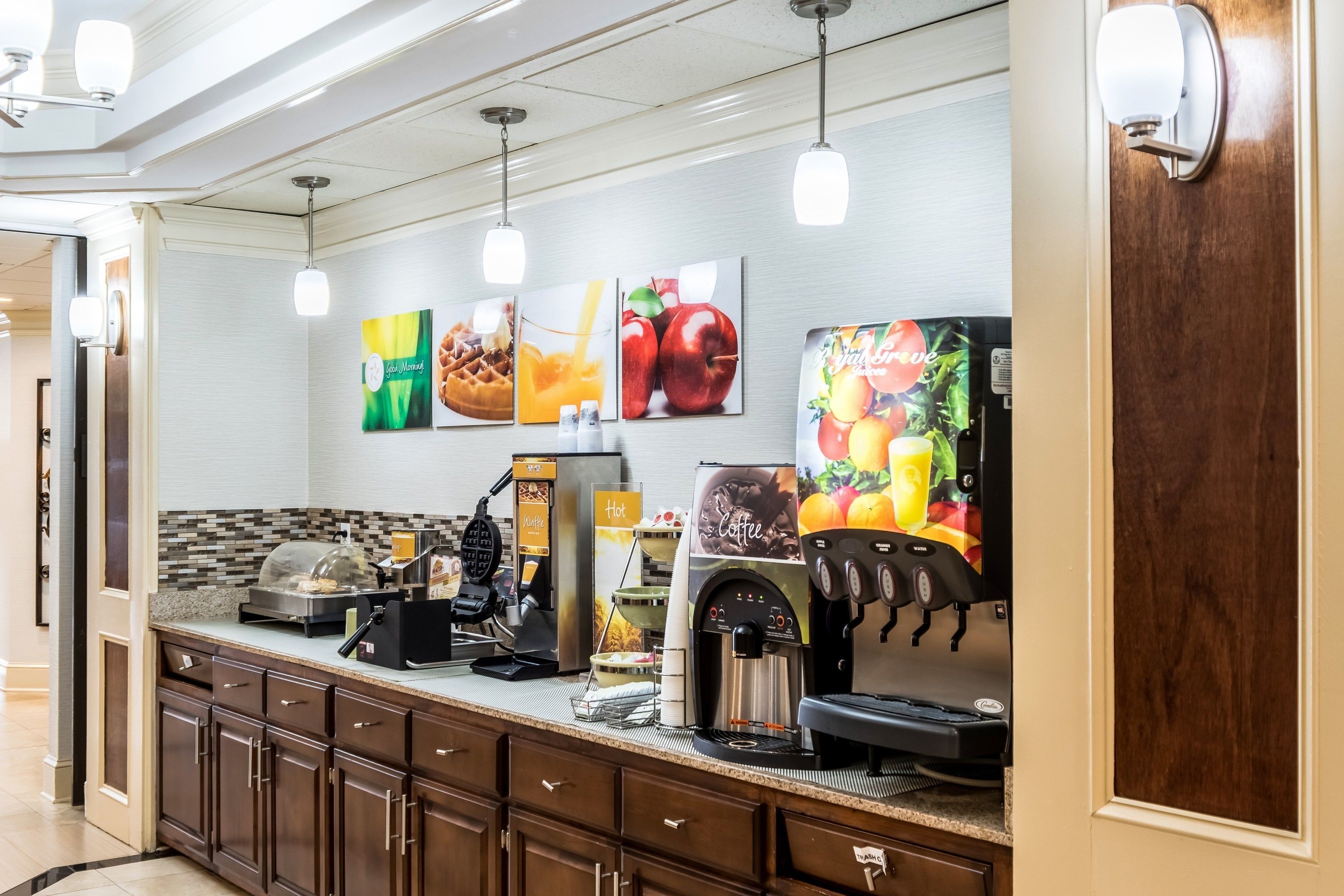 Una cocina de hotel con estación de café, máquina para gofres y cafetera.