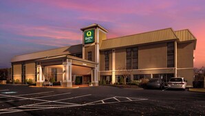 A Quality Inn hotel with a covered entrance, a parking lot, and a sunset sky.