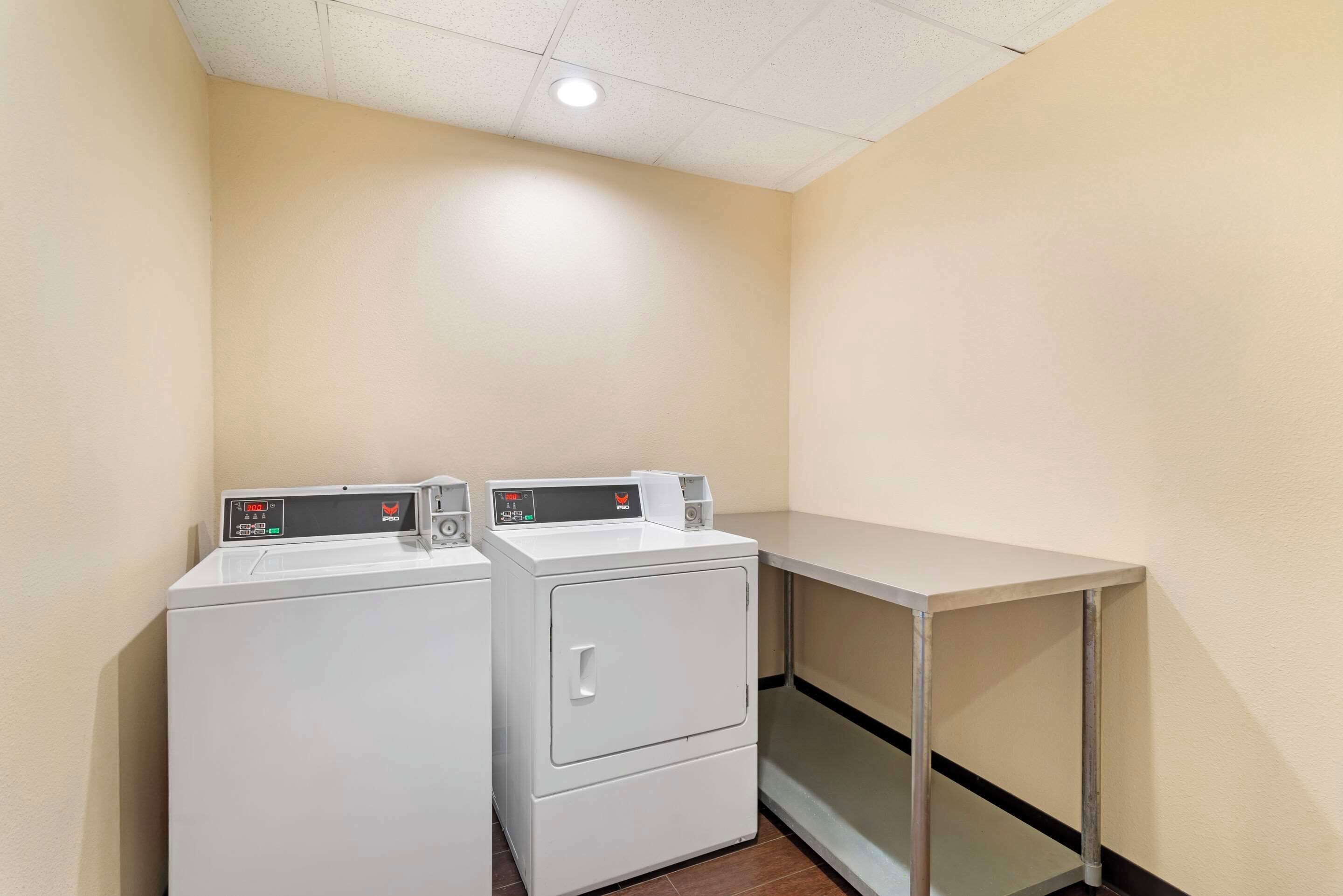 A laundry area with two white washing machines and a metal table.