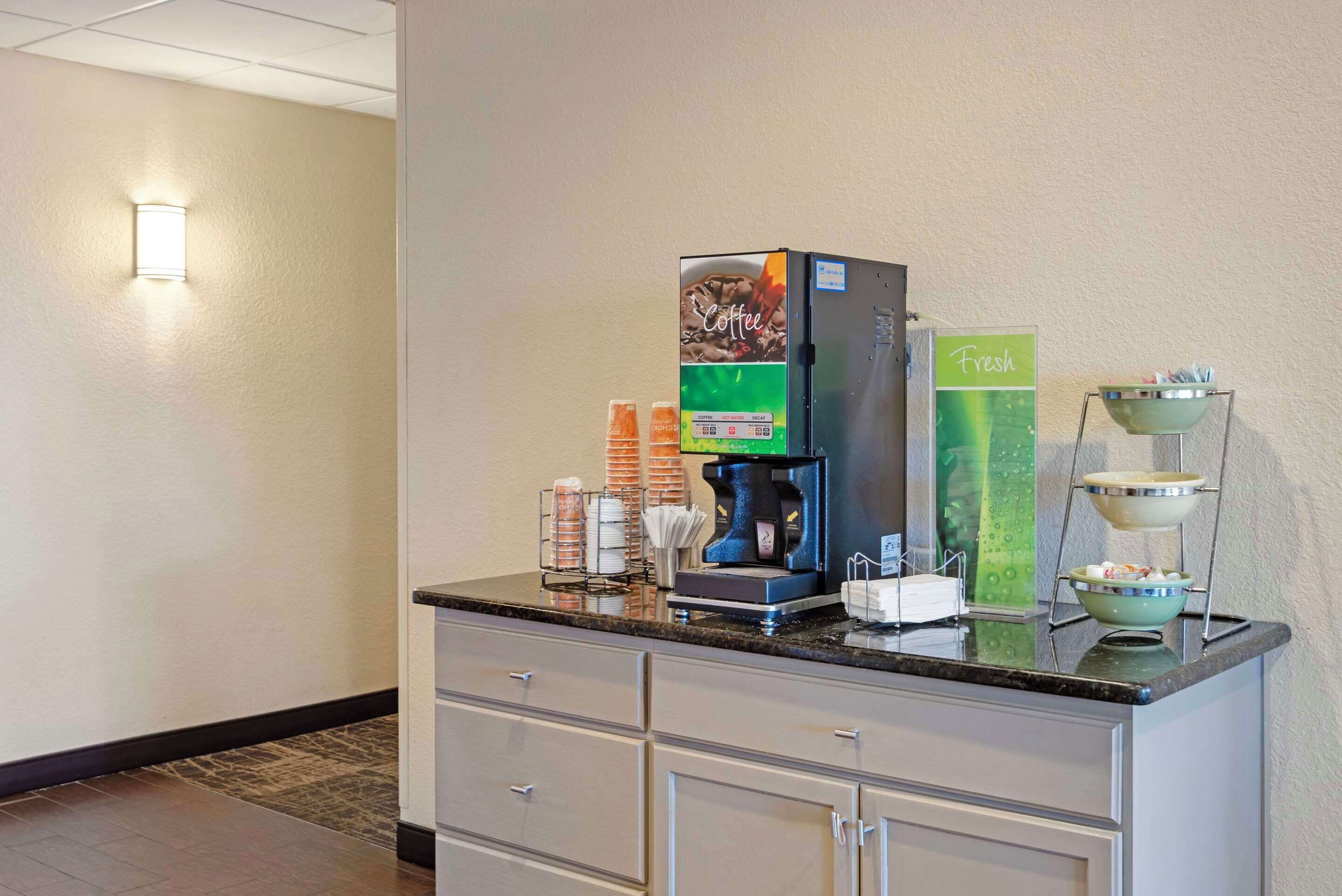 Un espace dédié au café, équipé d’une machine à café, de tasses et d’une pancarte indiquant que du café fraîchement préparé est disponible.