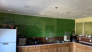 A kitchen with wooden cabinets, a white refrigerator, a sink, and a coffee machine. - Holiday Lodge (Greensboro)