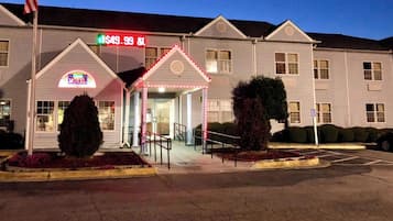A motel with a neon sign, a price sign, and a parking lot.