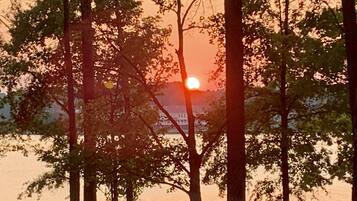 A sunset over a body of water with trees in the foreground.