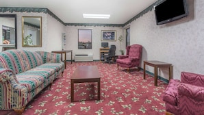 A room with a sofa, armchairs, a coffee table, a TV, and a desk with a chair.