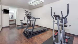 A fitness room with treadmills and elliptical machines, a TV mounted on the wall, and a mirror.