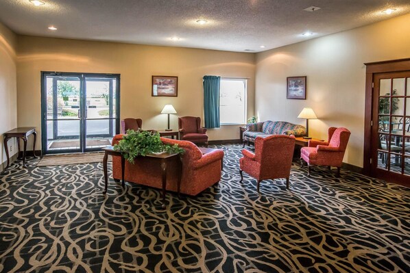 A lobby with a patterned carpet, several armchairs, a sofa, and a table with a plant.