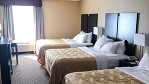A hotel room with two beds, a desk, and a window with curtains.