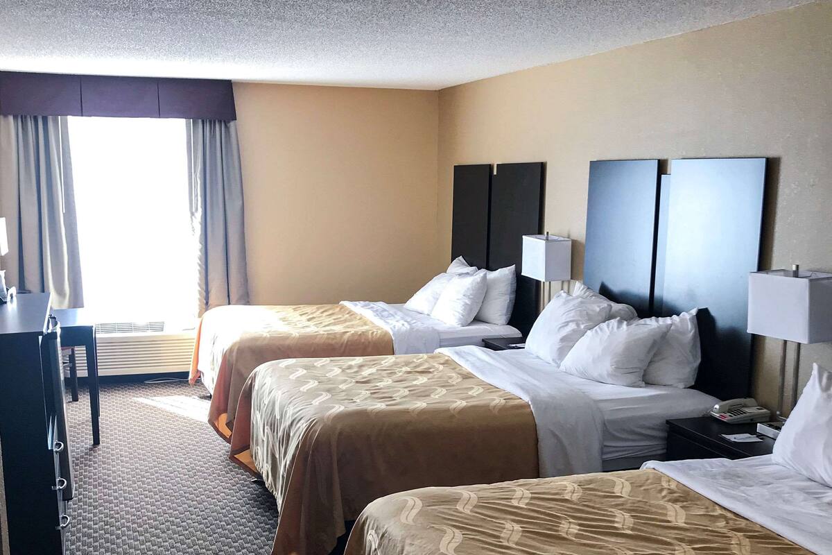 Ein Hotelzimmer mit zwei Betten, einem Schreibtisch und einem Fenster mit Vorhängen.