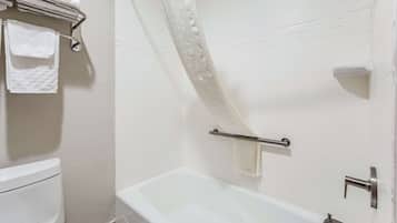 A bathroom with a bathtub, a toilet, and a towel rack with folded towels.