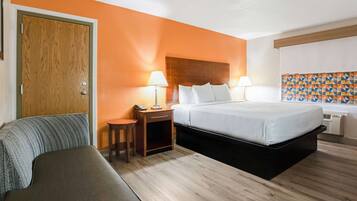 Una habitación de hotel con cama, mesitas de noche, escritorio, silla y armario.