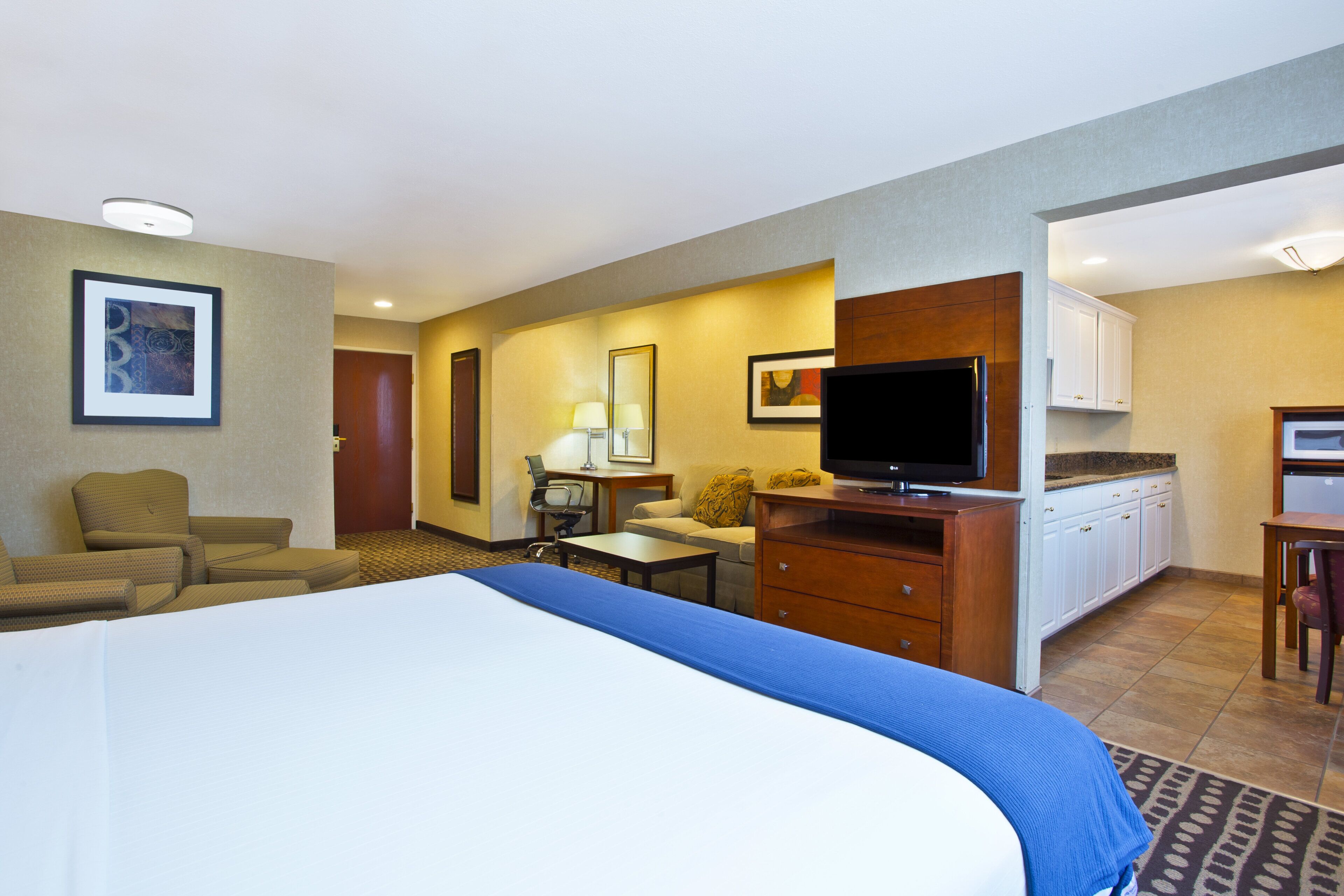 Une chambre d’hôtel équipée d’un lit, d’un bureau, d’une télévision, d’une chaise, d’un canapé et d’une kitchenette.