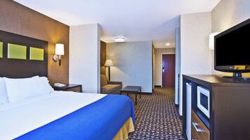 A hotel room with a bed, a desk, a television, and a lamp.