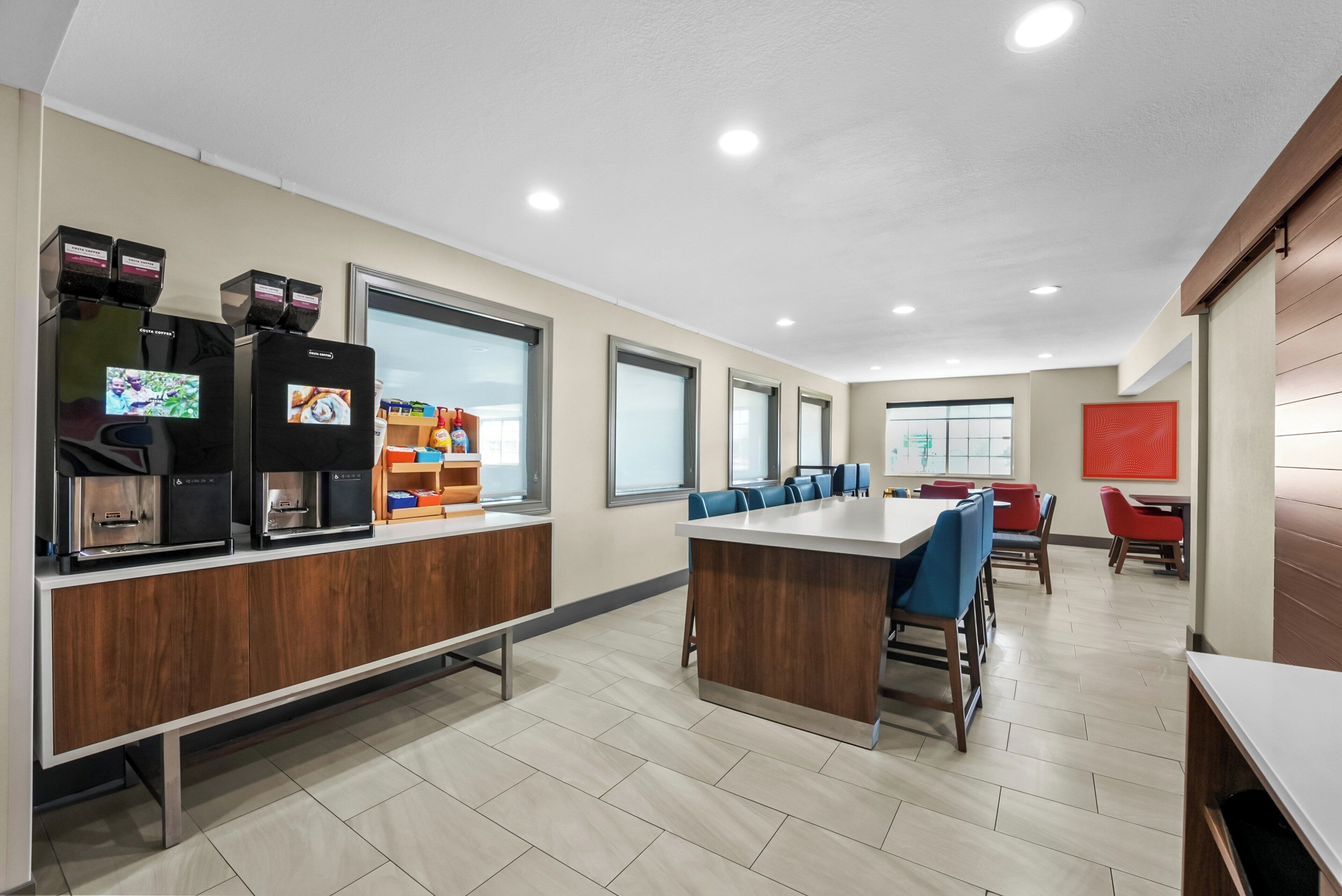 A modern cafeteria with a long counter, seating area, and vending machines.