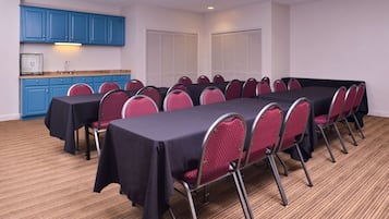 Una sala de conferencias con una mesa larga, sillas rojas y armarios azules.