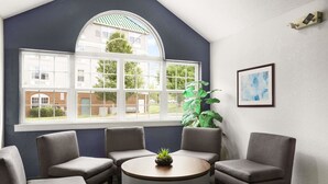 Ein Konferenzraum mit einem großen Bogenfenster, einem runden Tisch und vier grauen Stühlen.