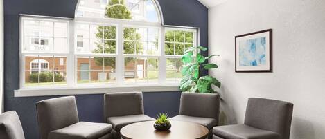A conference room with a large arched window, a round table, and four grey chairs.