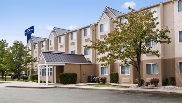 A Microtel Inn with a beige exterior, multiple windows, and a covered entrance. - Microtel Inn by Wyndham Louisville East (Louisville)