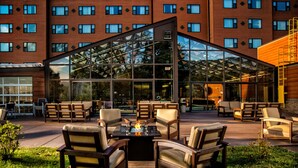 A hotel with a glass-enclosed patio area featuring outdoor seating and a fire feature. - Rocky Gap Casino & Resort (Cumberland)