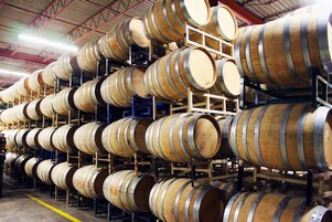 Un almacén con numerosos barriles de madera apilados en estantes.