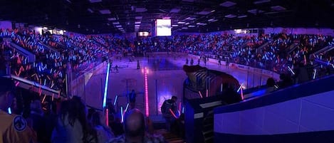 Una gran arena interior con una pista de hielo central rodeada de asientos escalonados.