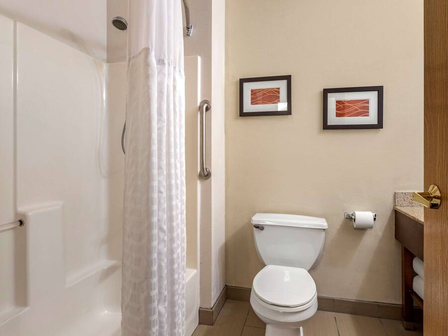 Un baño con una bañera blanca, un inodoro blanco y dos cuadros en la pared.